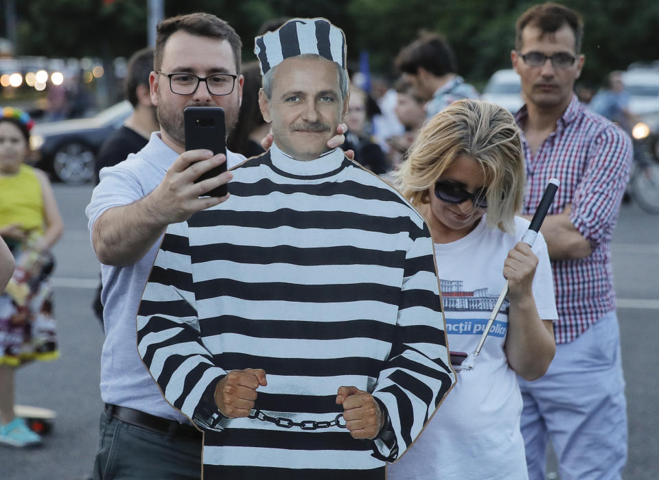 A man man takes a photo of himself next to at a cardboard depiction of Liviu Dragnea, the leader of the ruling Social Democratic party, as hundreds celebrate his sentencing to prison outside the government headquarters in Bucharest, Romania, Monday, May 27, 2019. Romania's most powerful politician was sentenced Monday to 3 and a half years in prison for official misconduct in a graft case. (AP Photo/Vadim Ghirda)