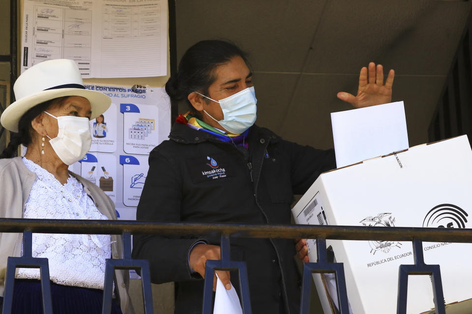 Accompanied by his mother, left, and wearing a mask to curb the spread of COVID-19, Yaku Perez, presidential candidate representing the Indigenous party Pachakutik, casts his ballot for president during general elections in Tarqui, Ecuador, Sunday, Feb. 7, 2021. (AP Photo/Marcelo Suquilanda)