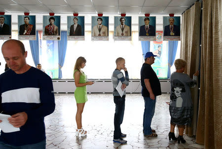 People wait in a queue in front of a voting booth during a parliamentary election at a polling station in Minsk, Belarus September 11, 2016. REUTERS/Vasily Fedosenko