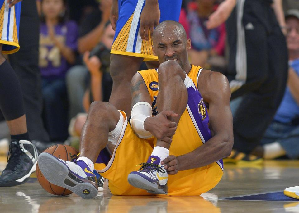 FILE - In this April 12, 2013 file photo, Los Angeles Lakers guard Kobe Bryant grimaces after being injured during the second half of their NBA basketball game against the Golden State Warriors, in Los Angeles. Bryant won't be back on the court for the Lakers this season. The Lakers said Bryant was examined by team physician Dr. Steve Lombardo, who determined that the left knee injury that has kept Bryant out of the lineup still hasn't healed. (AP Photo/Mark J. Terrill, File)