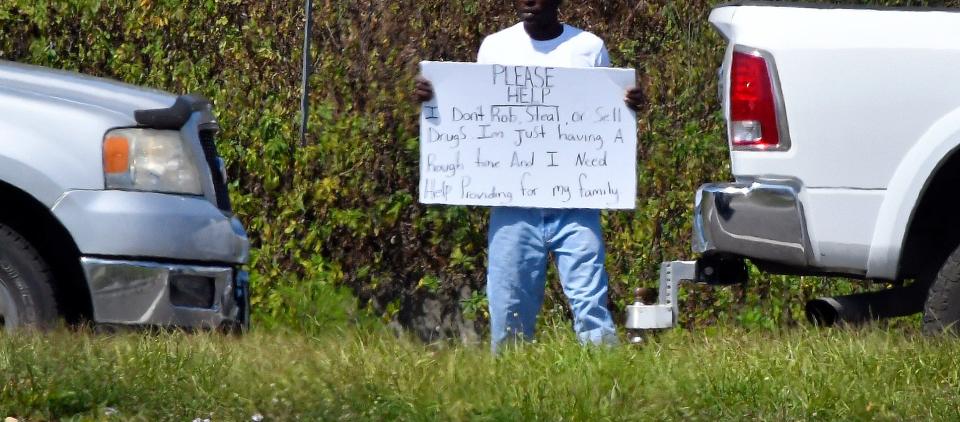 A man at the base of the southbound exit ramp of I-95 at State Road 520 in Cocoa. His sign states "I don't rob, steal, or sell drugs. I'm just having a rough time, and I need to help provide for my family".