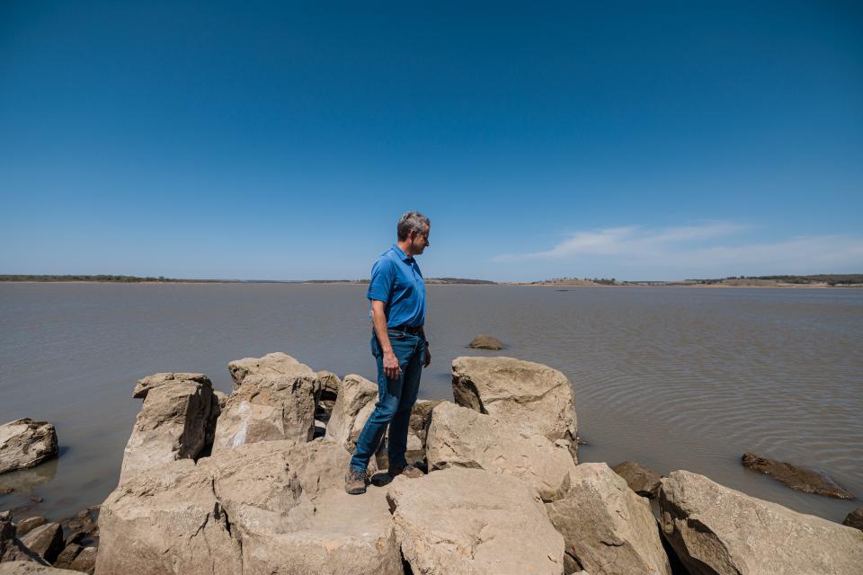 Terry Lauritsen, water utilities director, stands on rocks exposed by the dropping water level at Hulah Lake in April.