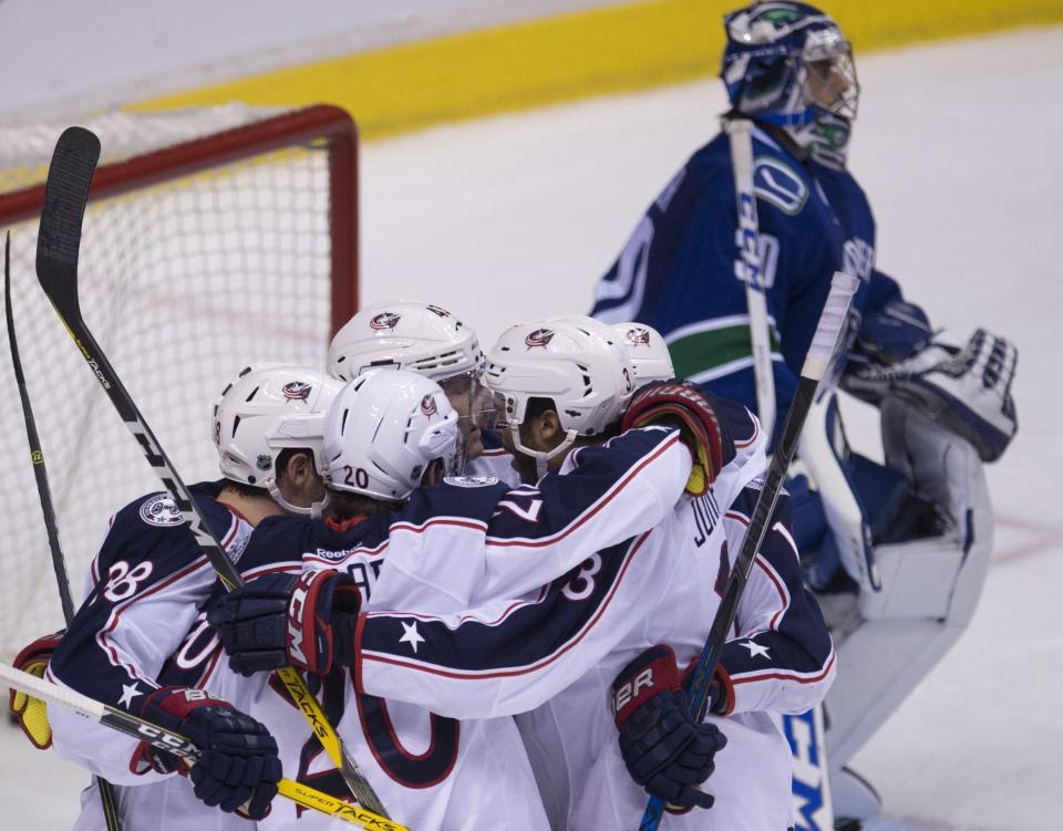 Vancouver Canucks goalie Ryan Miller (30) looks on as Columbus Blue Jackets left wing Brandon Saad (20) celebrates his goal with his teammates during the second period of an NHL hockey game, Sunday, Dec. 18, 2016 in Vancouver, British Columbia. (Jonathan Hayward/The Canadian Press via AP)