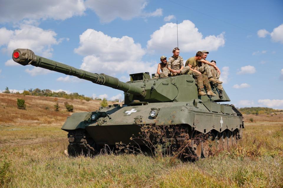 Crew sitting on a tank in a field.