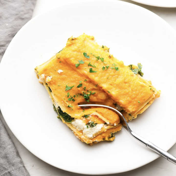 A slice of lasagna with squash sauce and almond ricotta, sprinkled with parsley