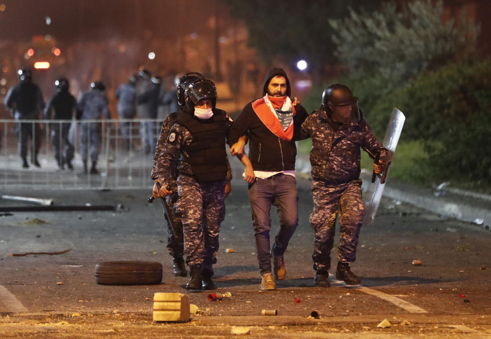 Riot police officers arrest an anti-government protester during a protest near the parliament square in downtown Beirut, Lebanon, Saturday, Dec. 14, 2019. The recent clashes marked some of the worst in the capital since demonstrations began two months ago. The rise in tensions comes as politicians have failed to agree on forming a new government. (AP Photo/Hussein Malla)