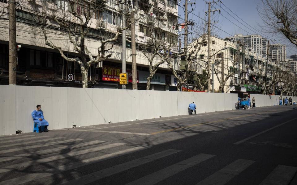 In Shanghai, perimeter fences surround a neighborhood that has been placed under strict lockdown restrictions... - Qilai Shen/Bloomberg