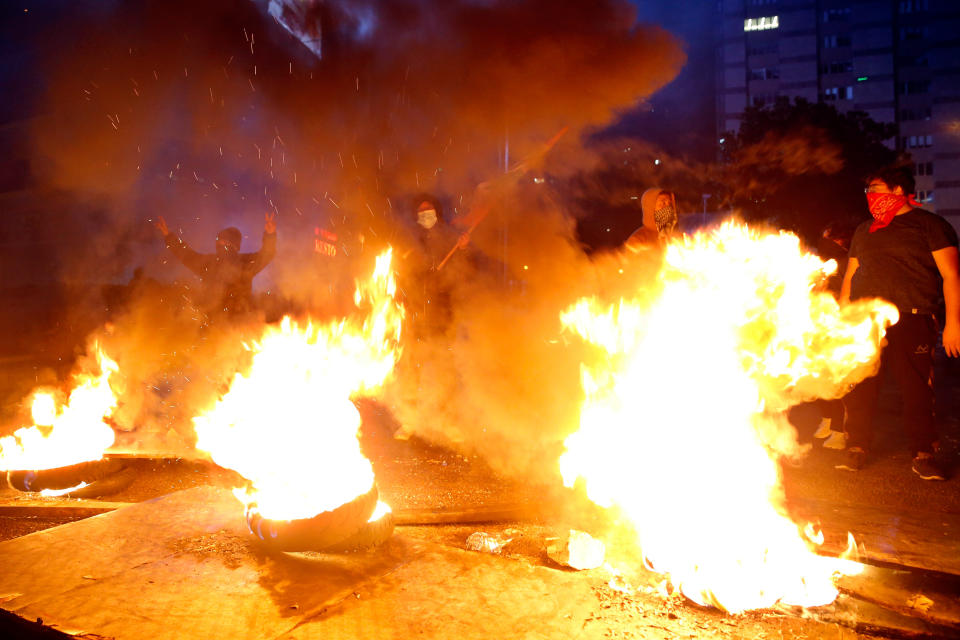 Anti-government demonstrators gather as burning tires block a road during a protest in Beirut, Lebanon, Thursday, Jan. 16, 2020. Lebanese protesters Thursday decried security forces' use of violence during rallies over the past two days, including attacks on journalists and the detention of over 100 people. (AP Photo/Bilal Hussein)