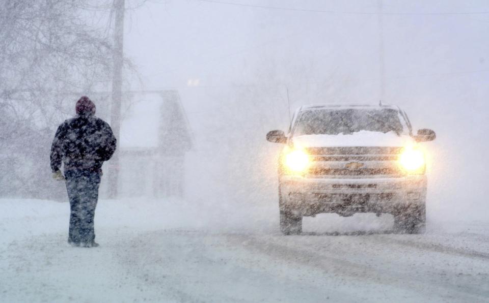 A pedestrian shares the road with motorists as he walks along State Road in North Adams, Mass., during a winter storm which brought blizzard conditions and heavy snow to the region, Sunday, Feb. 12, 2017. (Gillian Jones/The Berkshire Eagle via AP)