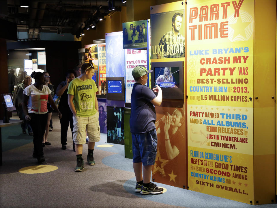 In this April 10, 2014, photo, people look at exhibits at the Country Music Hall of Fame and Museum in Nashville, Tenn. The facility is no longer bursting at the seams, thanks to a $100 million expansion that has more than doubled their space and allowed them to add more interactive and contemporary exhibits. (AP Photo/Mark Humphrey)