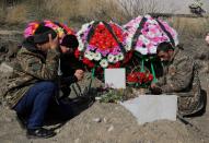 Men mourn at the grave of a fallen soldier, who was killed during the military conflict over the breakaway region of Nagorno-Karabakh, in Stepanakert