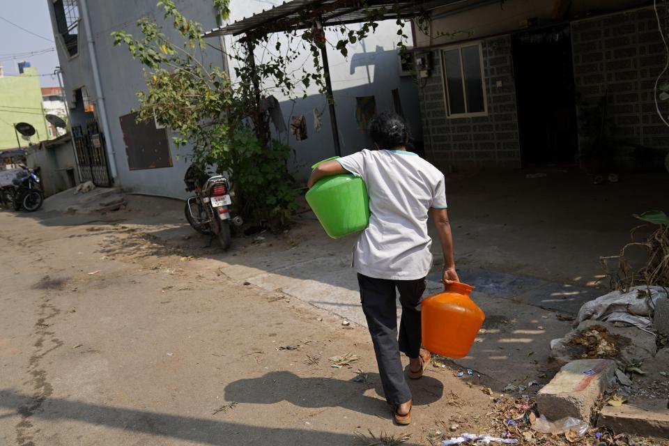 A woman carries home pots filled with potable water collected from a private tanker in Bengaluru, India, Monday, March 11, 2024. Bengaluru is witnessing an unusually hot February and March, and in the last few years, it’s received little rainfall in part due to human-caused climate change. (AP Photo/Aijaz Rahi)