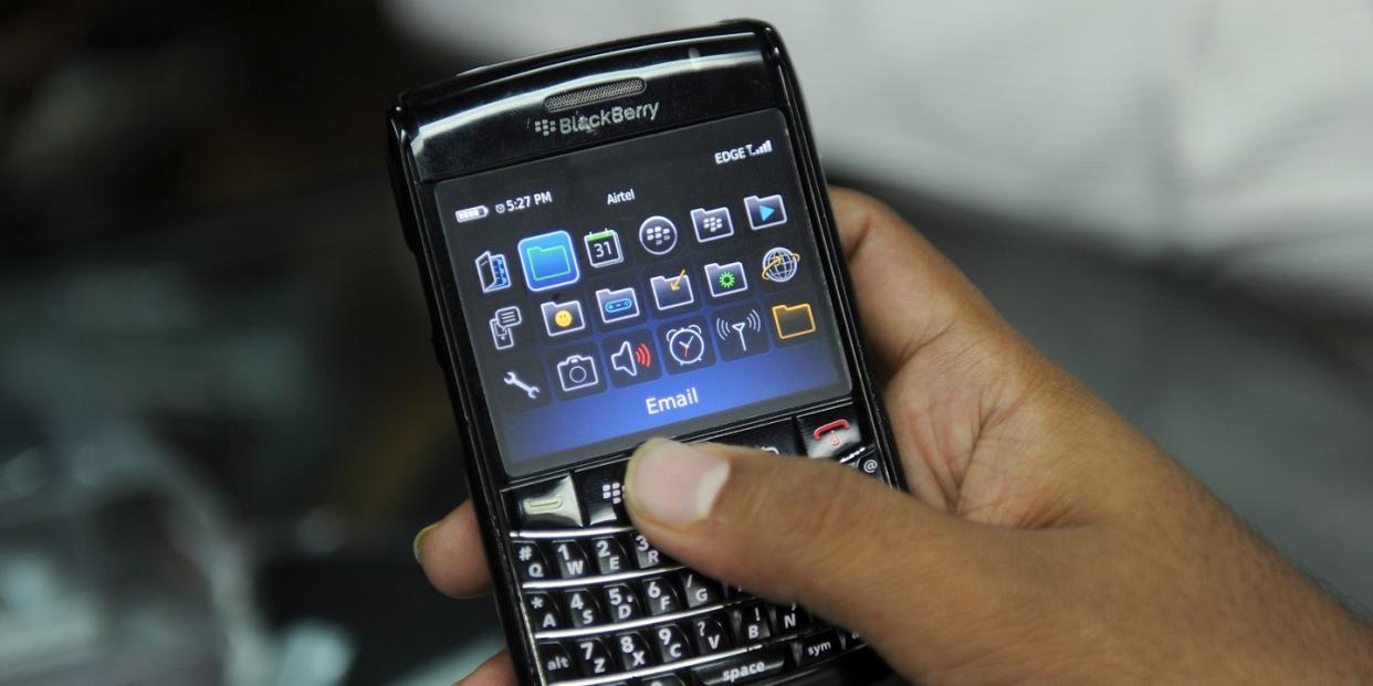 a closeup of a hand holding a blackberry smartphone, with several icons visible on the screen