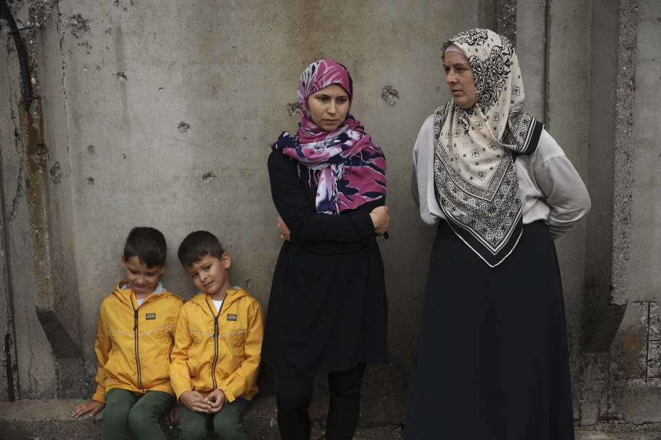 Women with their children wait for coffins containing remains of the victims of the 1995 Srebrenica genocide to arrive at the Memorial centre in Potocari, Bosnia, Friday, July 8, 2022. After surviving the 1995 Srebrenica massacre in which over 8,000 of their male relatives were killed, women from the small town in eastern Bosnia dedicated the remaining years of their lives to the re-telling of their trauma to the World, honoring the victims and bringing those responsible for the killings to justice. (AP Photo/Armin Durgut)