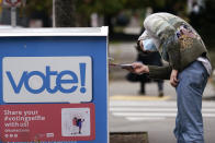 A voter turns sideways as he eyes the opening of a ballot drop box before placing his ballot inside it Wednesday, Oct. 28, 2020, in Seattle. Washington state is one of five states, along with Colorado, Hawaii, Oregon, and Utah, that conduct elections entirely by mail-in voting. (AP Photo/Elaine Thompson)