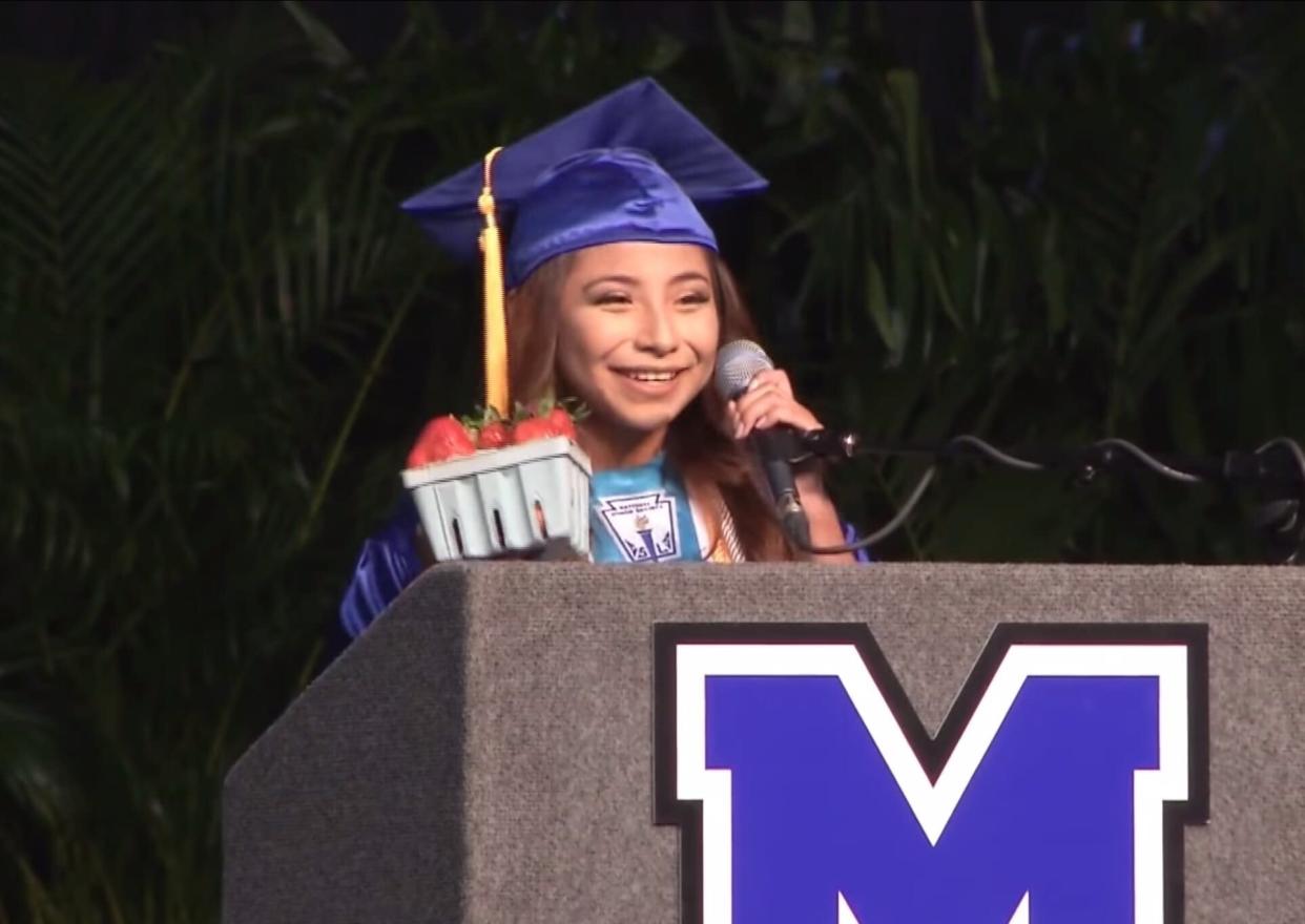 Brenda Alvarez-Lagunas holds a basket of strawberries up as she gives her Valedictorian speech. (Credit: Mulberry High School)