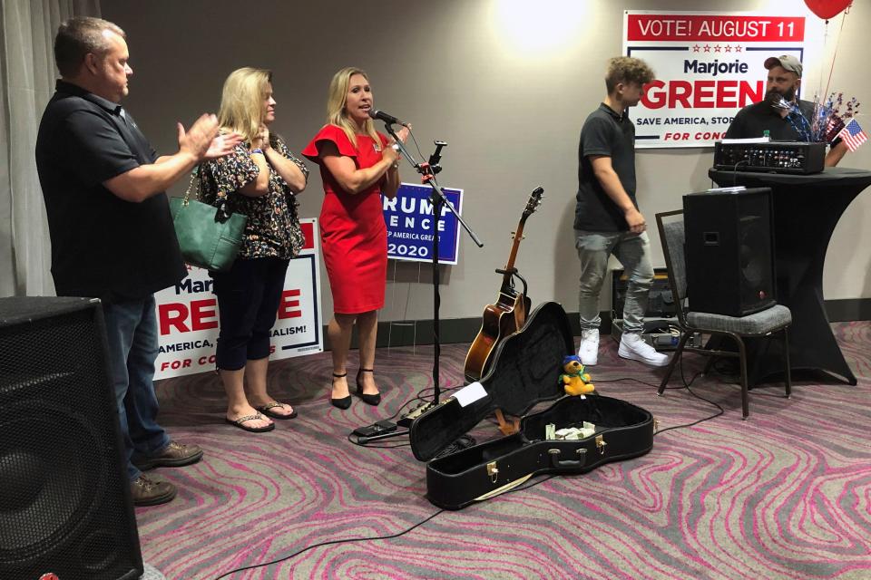 Construction executive Marjorie Taylor Greene, third from left, claps with her supporters at a watch party event, late Tuesday, Aug. 11, 2020, in Rome, Ga. Greene, criticized for promoting racist videos and adamantly supporting the far-right QAnon conspiracy theory, won the GOP nomination for northwest Georgia's 14th Congressional District. (AP Photo/Mike Stewart) ORG XMIT: GAMS