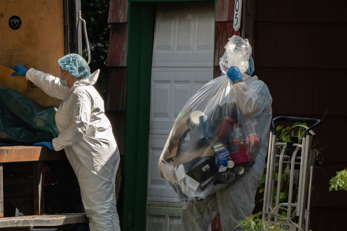 A crime laboratory officer moves a plastic bag of items as law enforcement searches the home of Rex Heuermann, Saturday, July 15, 2023, in Massapequa Park (AP)