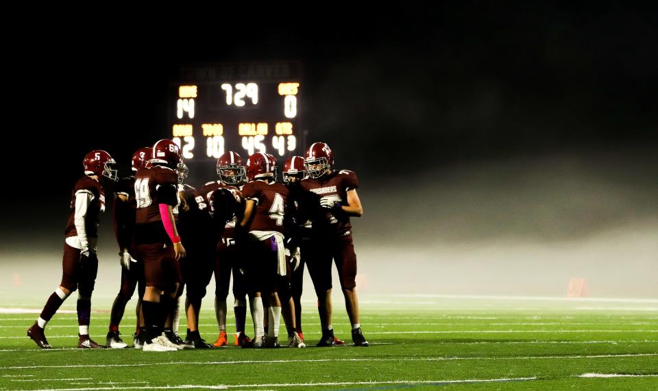 The Carver High football team huddled in a field of fog during a game against Randolph on Thursday, Oct. 6, 2022. The Crusaders won 21-0.