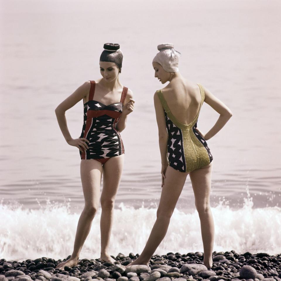 Two girls stand seaside: circa 1960