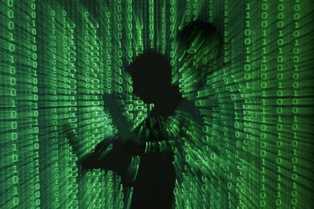 An illustration picture shows a projection of binary code on a man holding a laptop computer, in an office in Warsaw June 24, 2013. REUTERS/Kacper Pempel