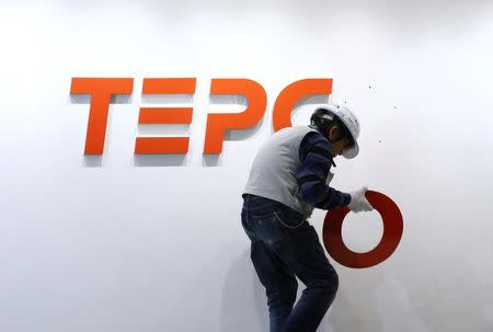 A worker puts up new logo of TEPCO Holdings and Tokyo Electric Power Company (TEPCO) Group on the wall ahead of the transition to a holding company system through a company split at the TEPCO headquarters in Tokyo, Japan, March 31, 2016. REUTERS/Masayuki Terazawa/Pool/File Photo