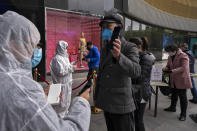 In this photo released by Xinhua News Agency, workers wearing protective suits check customers' health QR codes at the entrance of a re-opened shopping mall in in Wuhan in central China's Hubei province, Monday, March 30, 2020. Shopkeepers in the city at the center of China's virus outbreak were reopening Monday but customers were scarce after authorities lifted more of the anti-virus controls that kept tens of millions of people at home for two months. (Fei Maohua/Xinhua via AP)
