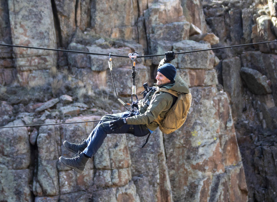 This image released by Nat Geo shows Bradley Cooper traversing across the canyon during his journey through the Pathfinder Canyon area in Wyoming, in a scene from “Running Wild with Bear Grylls: The Challenge," premiering on July 9. (Jeff Ellingson/Nat Geo via AP)