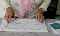 In this photo taken on Thursday, March 19, 2020, Magda Leonard, lays out a pattern for a face mask, meant to help protect from the spread of COVID-19, that she produced on her sewing machine at home in Edegem, Belgium. Leonard is making masks, along with her daughter, for family and friends and hopes to be able to produce enough to deliver to caregivers and local doctors. Belgium currently has a need for the masks due to a shortage in supply of industrially made masks. For most people, the new coronavirus causes only mild or moderate symptoms, such as fever and cough. For some, especially older adults and people with existing health problems, it can cause more severe illness, including pneumonia. (Gerd Moyson via AP)