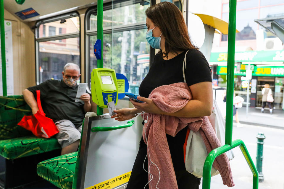 A woman tapping on to a Melbourne tram with the Myki ticketing system