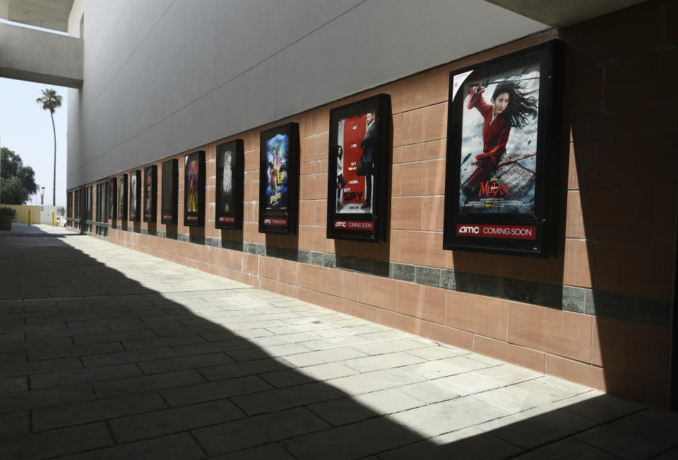 ARCHIVO – Afiches del próximo estreno e películas en un corredor vacío en un complejo de cines AMC Burbank Town Center 8 cerrado el 29 de abril de 2020 en Burbank, California. Tras varios tropiezos iniciales, la industria cinematográfica espera contar otra vez con estrenos a finales de agosto. Pero para grandes producciones como la recién postergada “Tenet”, eso podría significar repensar el fin de semana de estreno y volver a un lanzamiento más gradual en territorios internacionales e incluso nacionales. Atrás quedaron los estrenos globales simultáneos. Tal vez no sea lo ideal, pero los dueños de cines dicen que si no tienen nuevas películas pronto, quizás no lleguen al 2021. (Foto AP/Chris Pizzello, archivo)