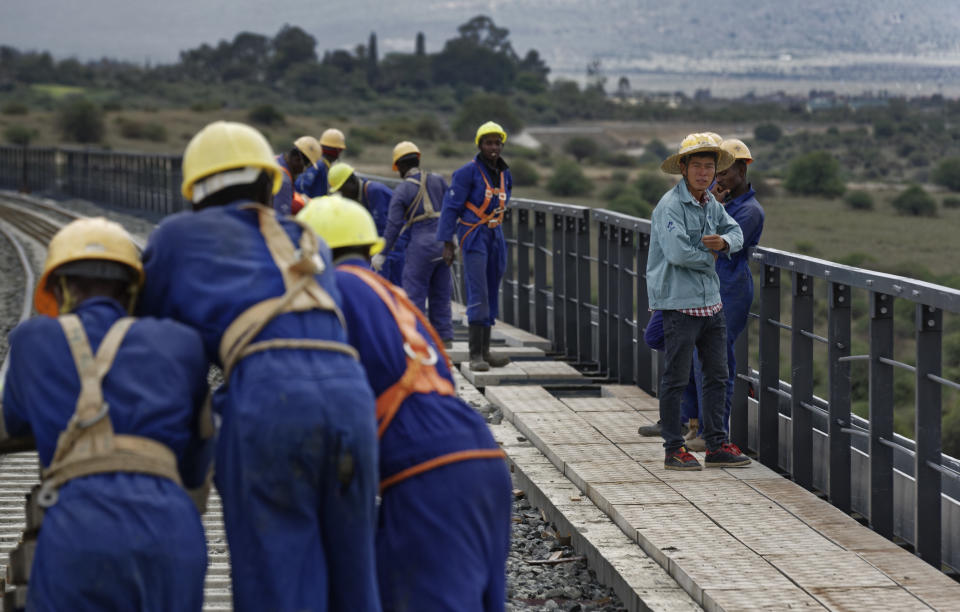 FILE - In this Wednesday, Nov. 23, 2016 file photo, Kenyan laborers and a Chinese foreman, right, work to finish the construction of an existing bridge that goes across a corner of Nairobi National Park in Nairobi, Kenya. African leaders in 2020 are asking what China can do for them as the coronavirus pandemic threatens to destroy economies across a continent where Beijing is both the top trading partner and top lender. (AP Photo/Ben Curtis, File)