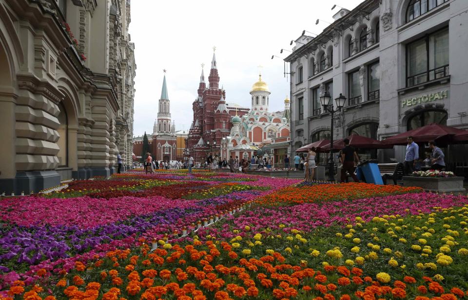 People walk past flowers located near GUM department store, Red Square and the Kremlin in Moscow