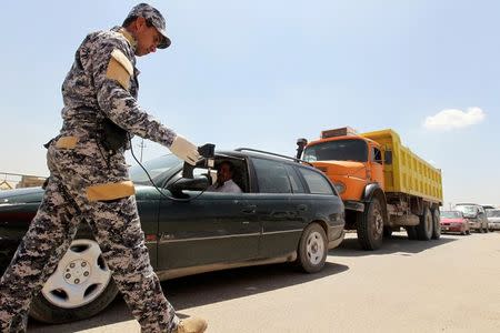 A policeman uses a scanning device to inspect a vehicle at the entrance to Sadr City, northeastern Baghdad April 24, 2010. REUTERS/Mohammed Ameen/File Photo