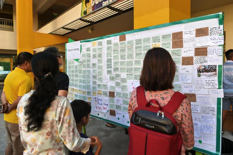 People look at condolence messages posted on a board in memory of the victims from an earthquake on Malaysia's Mount Kinabalu, at the Tanjong Katong Primary School in Singapore, on June 7, 2015