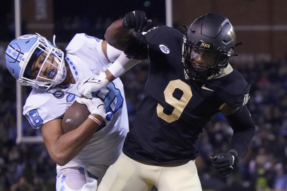 North Carolina tight end Bryson Nesbit (18) is knocked out of bounds by Wake Forest defensive back Chelen Garnes (9) during the first half of an NCAA college football game in Winston-Salem, N.C., Saturday, Nov. 12, 2022. (AP Photo/Chuck Burton)