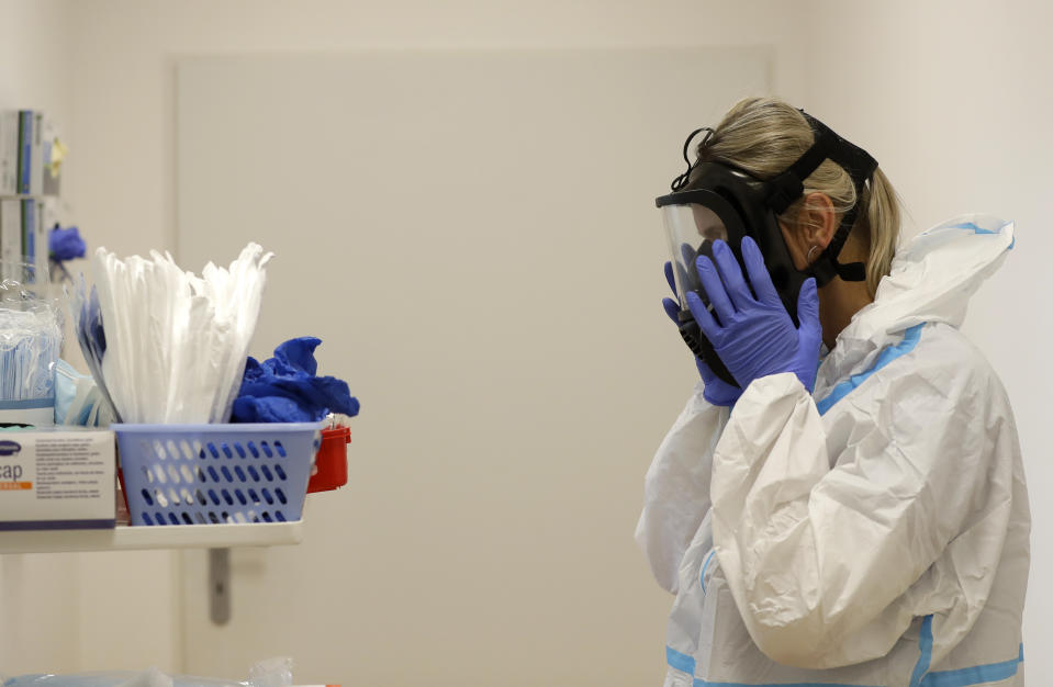 A health care worker puts on personal protective equipment (PPE) before tending to COVID-19 patients at an intensive care unit (ICU) at a hospital in Kyjov, Czech Republic, Thursday, Oct. 22, 2020. With cases surging in central Europe, some countries are calling in soldiers, firefighters, students and retired doctors to help shore up buckling health care systems. (AP Photo/Petr David Josek)