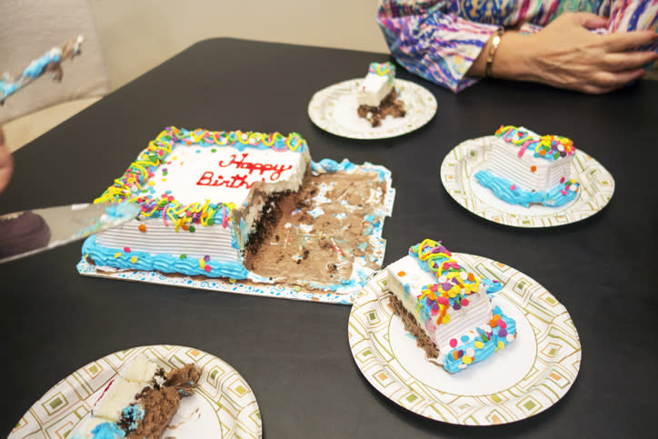 Person cutting a birthday cake with slices on plates at a work celebration