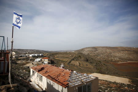 An Israeli flag flutters as a Jewish settler works on the construction of a house in the unauthorised Jewish settler outpost of Achiya, south of the West Bank city of Nablus January 5, 2016. REUTERS/Ronen Zvulun