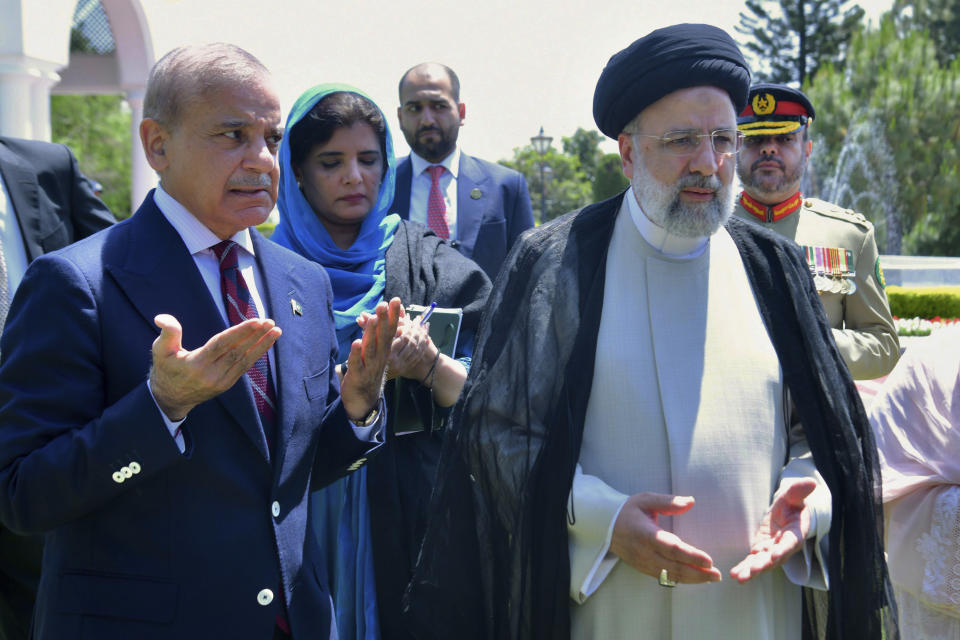 In this photo released by Prime Minister Office, Iranian President Ebrahim Raisi, right, with Pakistan's Prime Minister Shehbaz Sharif, left, prays after planting a tree in the prime minister house in Islamabad, Pakistan, Monday, April 22, 2024. (Prime Minister Office via AP)