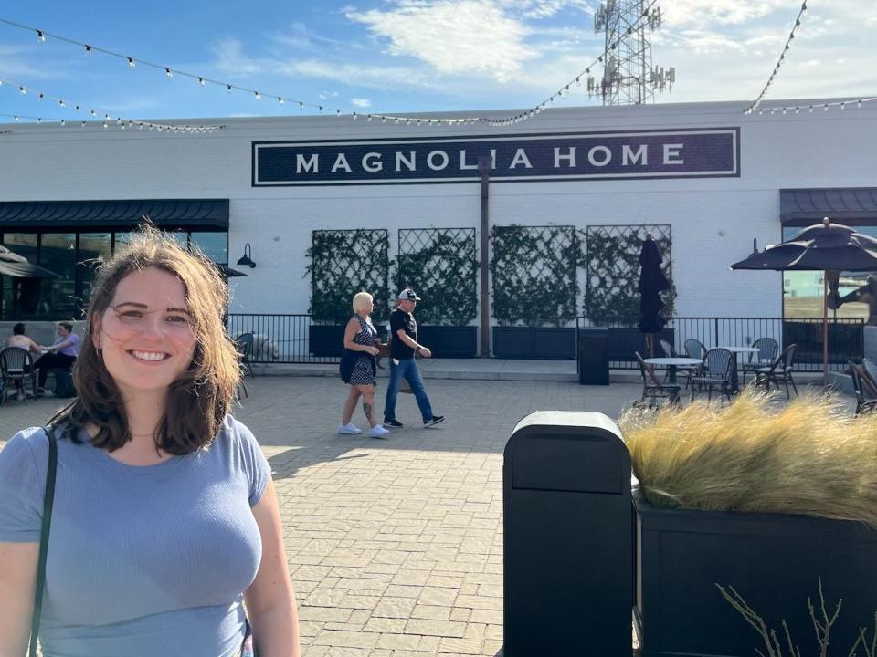 A photo of a woman in front of a white building that says Magnolia Home.