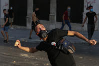 Anti-government protesters throw stones toward riot police during a protest marking the first anniversary of the massive blast at Beirut's port, near Parliament Square, In Beirut, Lebanon, Wednesday, Aug. 4, 2021. United in grief and anger, families of the victims and other Lebanese came out into the streets of Beirut on Wednesday to demand accountability as banks, businesses and government offices shuttered to mark one year since the horrific explosion. (AP Photo/Bilal Hussein)