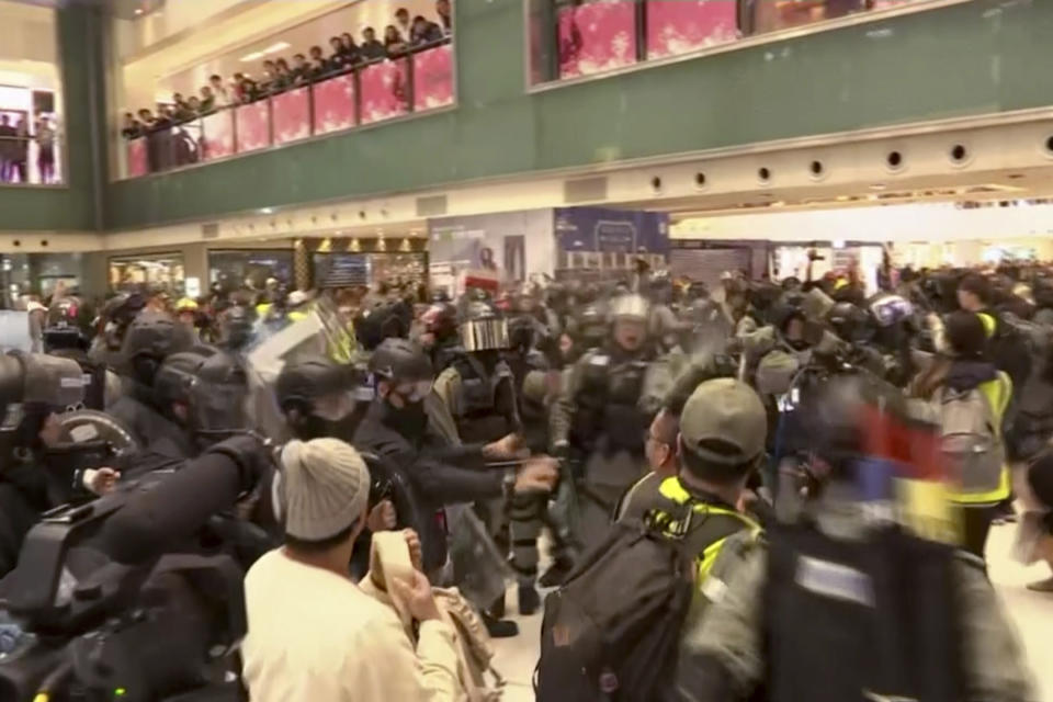 In this image made from video, police and protester scuffle at a shopping mall in Sha Tin district in Hong Kong, with shoppers watch from balconies above, Sunday, Dec. 15, 2019. The rally, which had a Christmas shopping theme, was the latest in a series of demonstrations, which have beset Hong Kong for more than six months.(AP Photo)