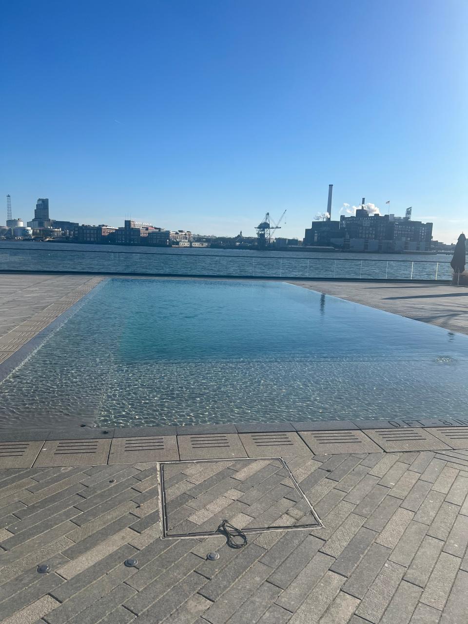 Outdoor urban infinity pool overlooking a city skyline and harbor on a clear day