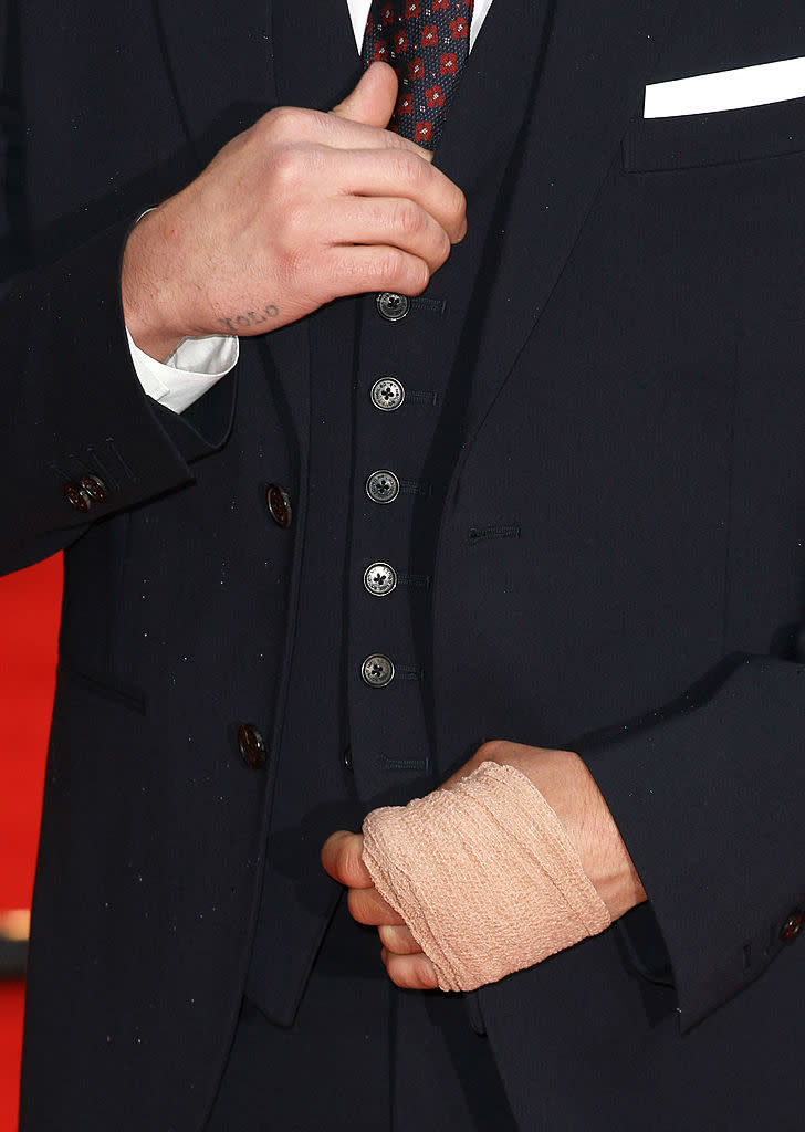 Zac's small "YOLO" tattoo visible on his right hand as he adjusts his suit