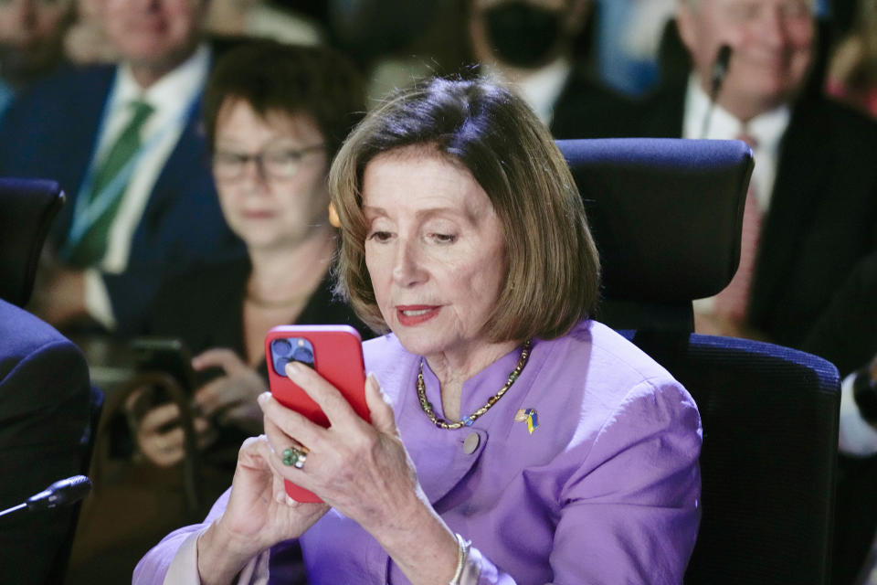 House Speaker Nancy Pelosi of Calif., looks at her phone as she waits for President Joe Biden to arrive to speak during the COP27 U.N. Climate Summit, Friday, Nov. 11, 2022, at Sharm el-Sheikh, Egypt. (AP Photo/Alex Brandon)