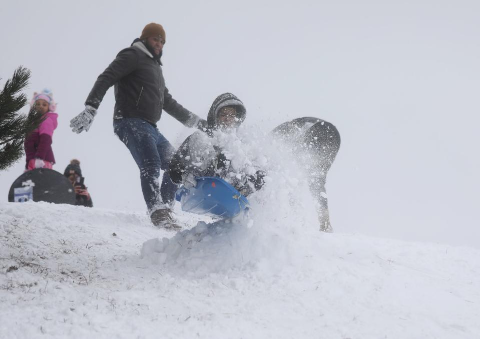 Orlando Melendez, 16, of Rochester goes airborne with a face full of snow Sunday after hitting a mogul while sledding on a hill at Cobbs Hill Reservoir. Melendez's father, Reynier Santiago, behind him, gave a push to get him going down the hill.