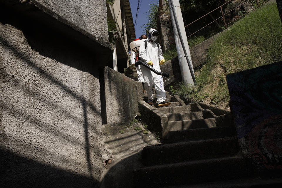 Water utility workers from CEDAE disinfect in the Vidigal favela in an effort to curb the spread of the new coronavirus, in Rio de Janeiro, Brazil, Friday, April 24, 2020. (AP Photo/Silvia Izquierdo)