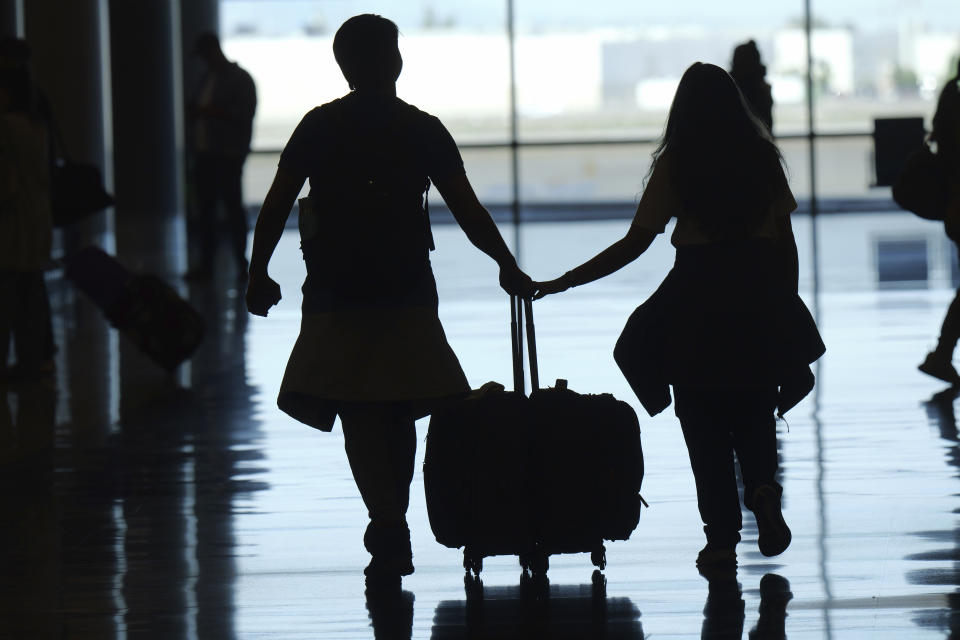 Travelers walk through Salt Lake City International Airport Friday, May 24, 2024, in Salt Lake City. A record number of Americans are expected to travel over the 2024 Memorial Day holiday. (AP Photo/Rick Bowmer)