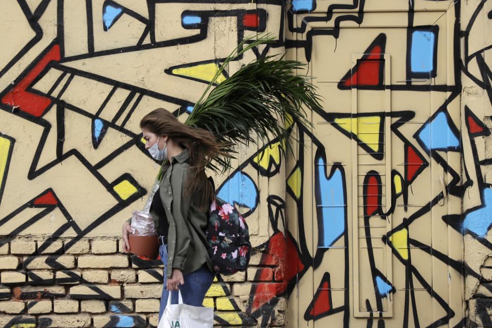 A woman wearing a face mask to protect from coronavirus, carries a plant in Prague, Czech Republic, Wednesday, Oct. 7, 2020. Coronavirus infections in the Czech Republic hit a new record high, surpassing 4,000 cases in one day for the first time. (AP Photo/Petr David Josek)